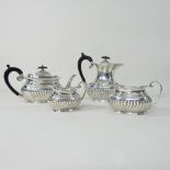 An Edwardian silver four piece tea service, of oval half gadrooned shape, comprising a teapot,