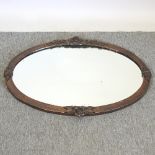 An early 20th century oval shaped copper framed wall mirror,