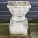 A large reconstituted stone garden pot, with celtic design, on a pedestal base,