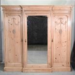 An antique pine triple wardrobe, with a central mirrored door, with a fitted interior,