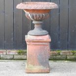 A terracotta urn, on a pedestal base,