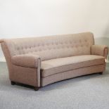 An Art Deco brown upholstered sofa, with a curved button back,
