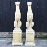 A pair of reconstituted stone models of greyhounds, each on a plinth,