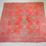 A Persian woollen rug, with geometric design, on a red ground,
