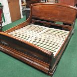 A modern cherrywood sleigh double bedstead, with a slatted base and pull out drawer,