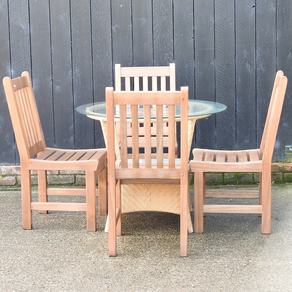 A woven garden table, with a glass top, together with a set of four teak garden chairs,