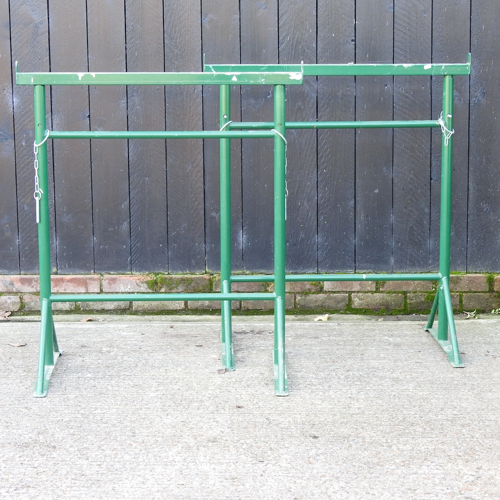 A pair of green painted adjustable scaffold stands,