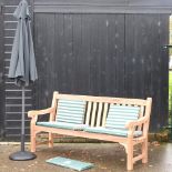 A hardwood garden bench, with white and green striped loose cushions, and cover, 183cm,