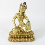 A reproduction gilt bronze figure of a deity, resting an elbow on his knee,
