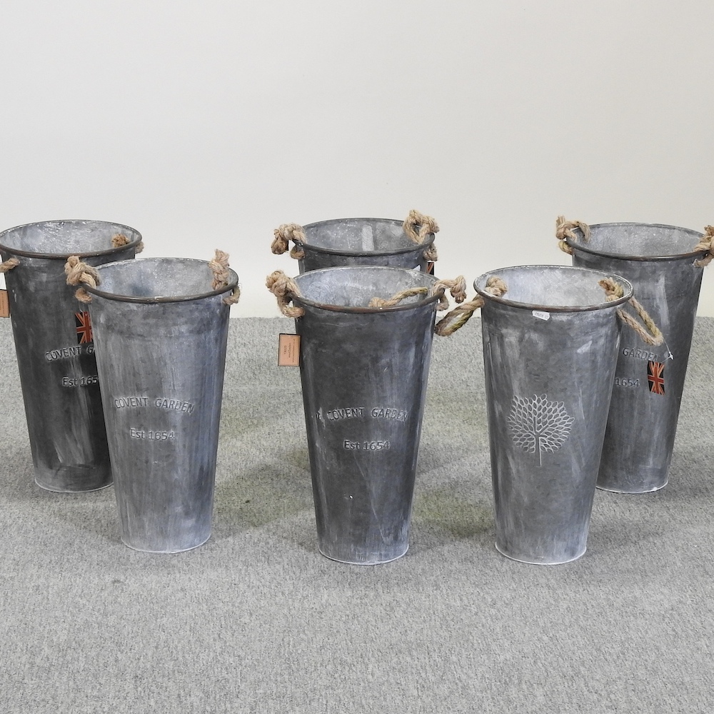 A set of six circular galvanized tall metal planters,