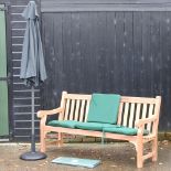 A hardwood garden bench, with green loose cushions, and cover, 183cm,