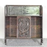 A carved oak hanging cabinet, with an inset mirror,