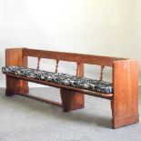An antique pine pew, of large proportions, with a cushion seat,