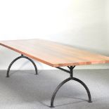 A modern hardwood dining table, on a tubular metal base,