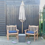 A pair of hardwood garden armchairs, with blue loose cushions, and covers,