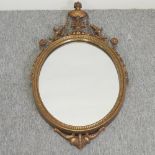 A Victorian style oval gilt framed wall mirror, surmounted by an urn,