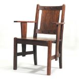 An early 20th century Arts and Crafts oak elbow chair, with curved arms,