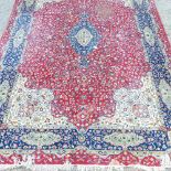 A Persian woollen carpet, with a central medallion, on a red ground,