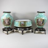 An early 20th century French porcelain garniture of three vases, on stands, painted with figures,