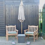 A pair of hardwood garden armchairs, with green striped loose cushions, and covers,