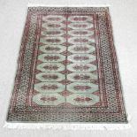 A Bokhara style rug, with rows of medallions, on a green ground,