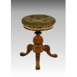 A Victorian carved walnut adjustable piano stool, the buttoned seat in olive green velour, on a
