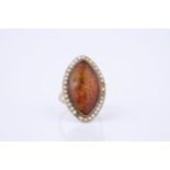 A Victorian amber and seed pearl ring, the marquise shaped amber within a border of seed pearls,