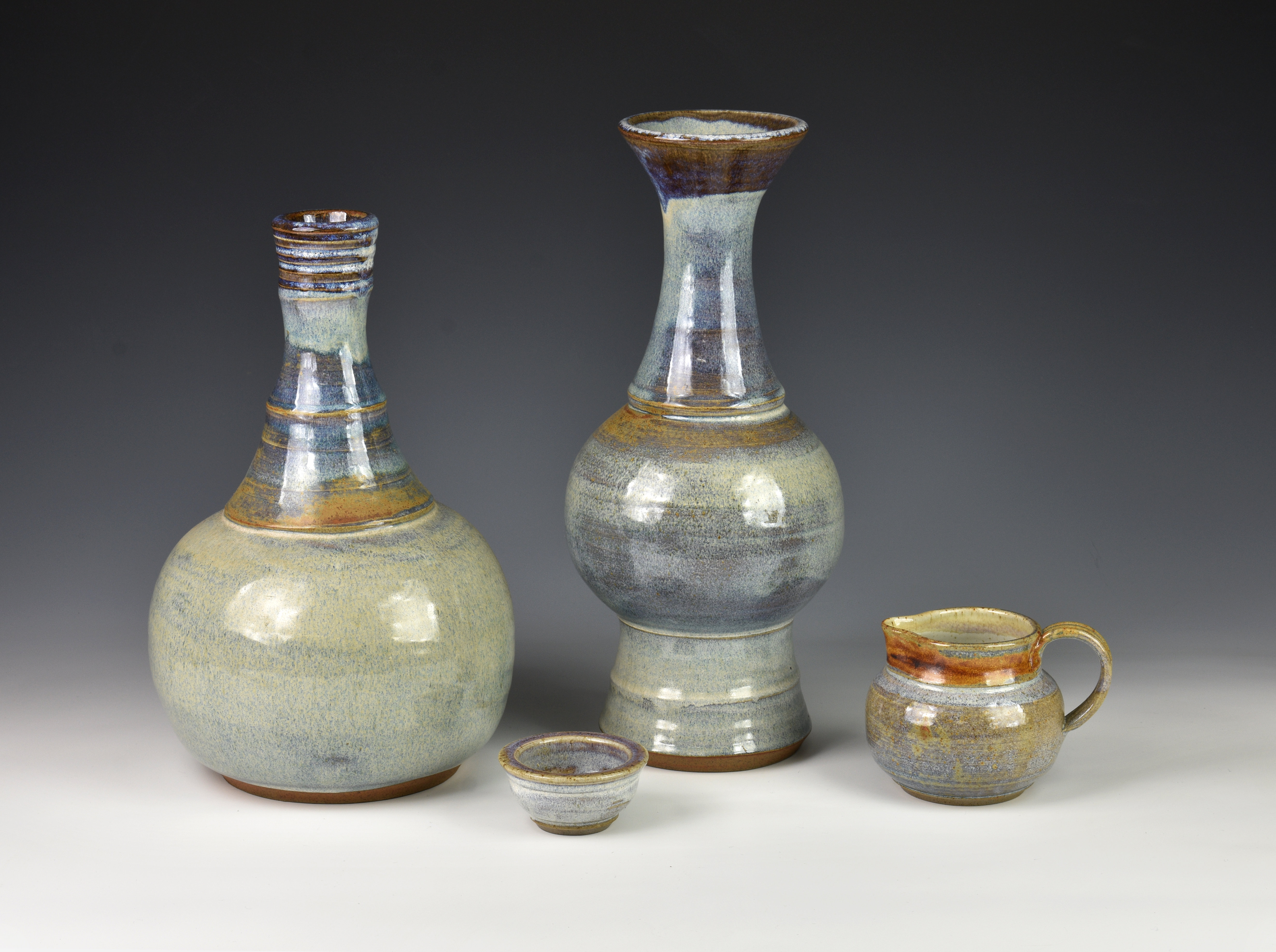 Two Guernsey Pottery vases, the first of bottle form with elongated neck, decorated in shades of