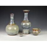Two Guernsey Pottery vases, the first of bottle form with elongated neck, decorated in shades of