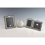 Four Elizabeth II silver mounted easel back photo frames, comprising of one embossed with floral and