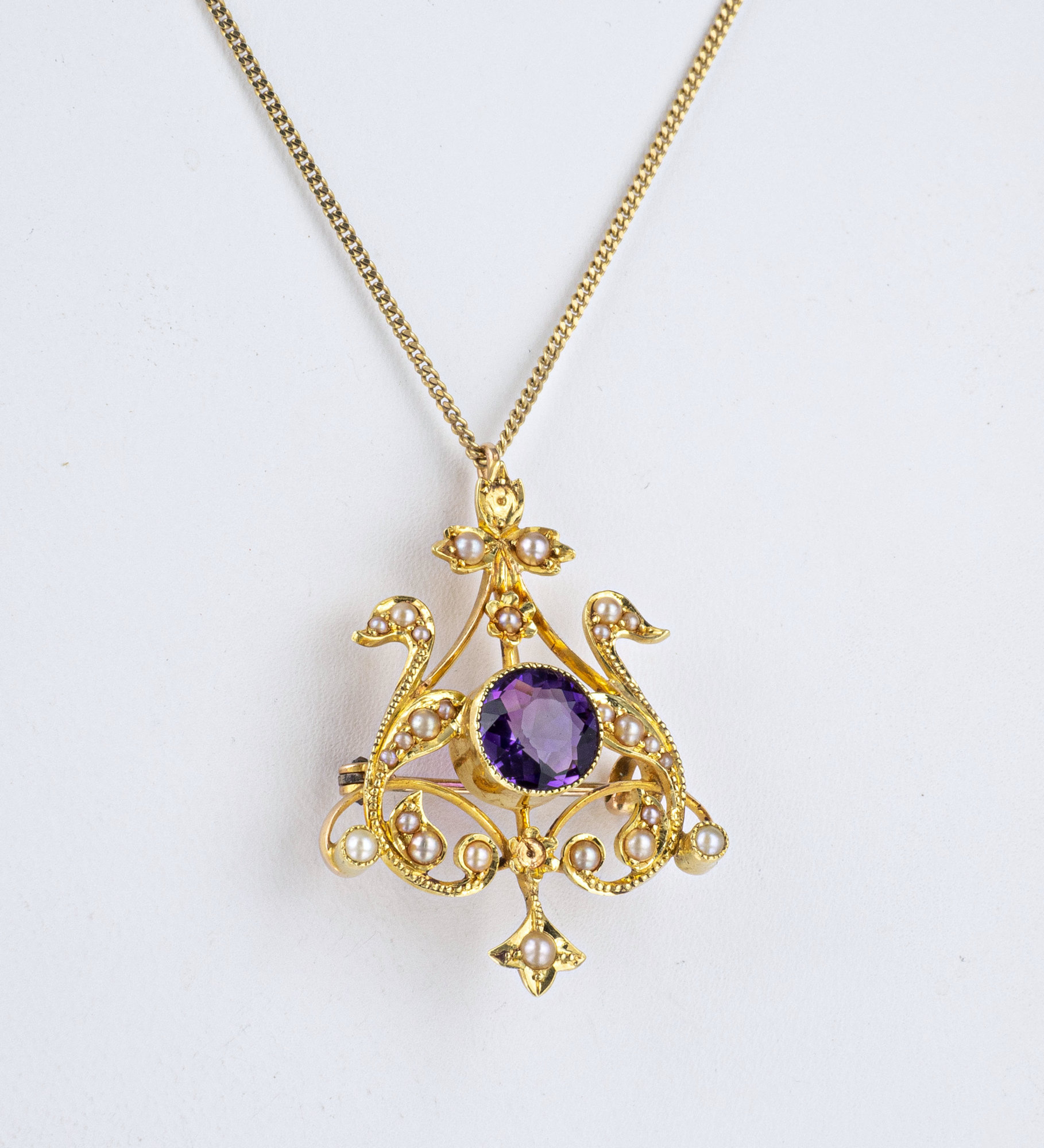 An Edwardian 18ct yellow gold, amethyst and seed pearl pendant brooch, the openwork, heart shaped