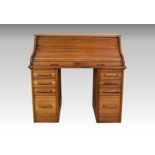 A 1930s honey oak rolltop desk, the serpentine tambour front enclosing a fitted interior with two