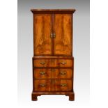 A 20th century Georgian style figured walnut drinks cabinet, in the form of a miniature tallboy, the