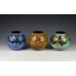 Three Guernsey pottery vases, each of globular form, each decorated with floral design on blue,
