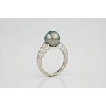 A black Tahitian pearl, diamond and platinum ring., The 10mm Tahitian black pearl set into