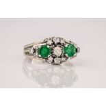 A French 18ct white gold, emerald and diamond ring, mid-century, set with two round cut emeralds and