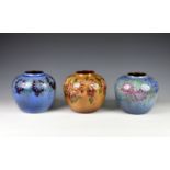 Three Guernsey Pottery vases, each of compressed ovoid form, decorated with flowers on blue and