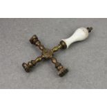 An unusual antique bronze cruciform triple pastry stamp, having a white pottery baluster handle, 8½