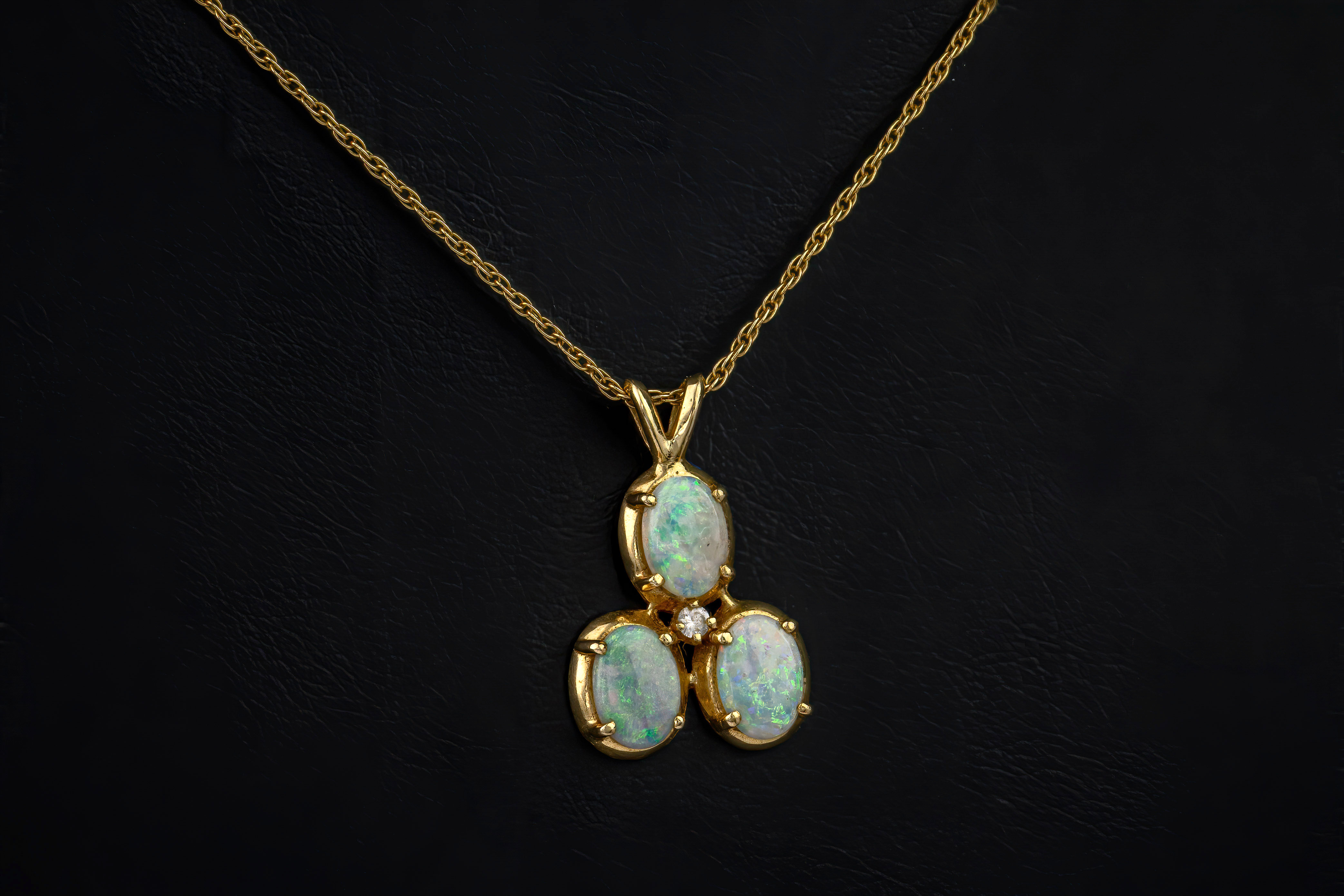 A 14ct gold, opal and diamond pendant necklace, featuring three oval opals set around a smaller,