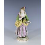 A Meissen style figure of a girl holding a music book, early 20th century, Continental, in a green