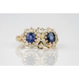 A yellow gold, sapphire and old cut diamond cluster ring, featuring two round cut sapphires