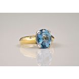 An 18ct gold, blue topaz and diamond ring, London hallmarks, the oval cut topaz over a bladed