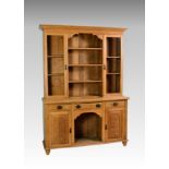 A late Victorian light oak dresser, the flare cornice over a part glazed and shelves closed back,