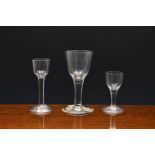 Three mid-18th century plain stem wine glasses, c.1750-1770, the first a large goblet with ogee bowl