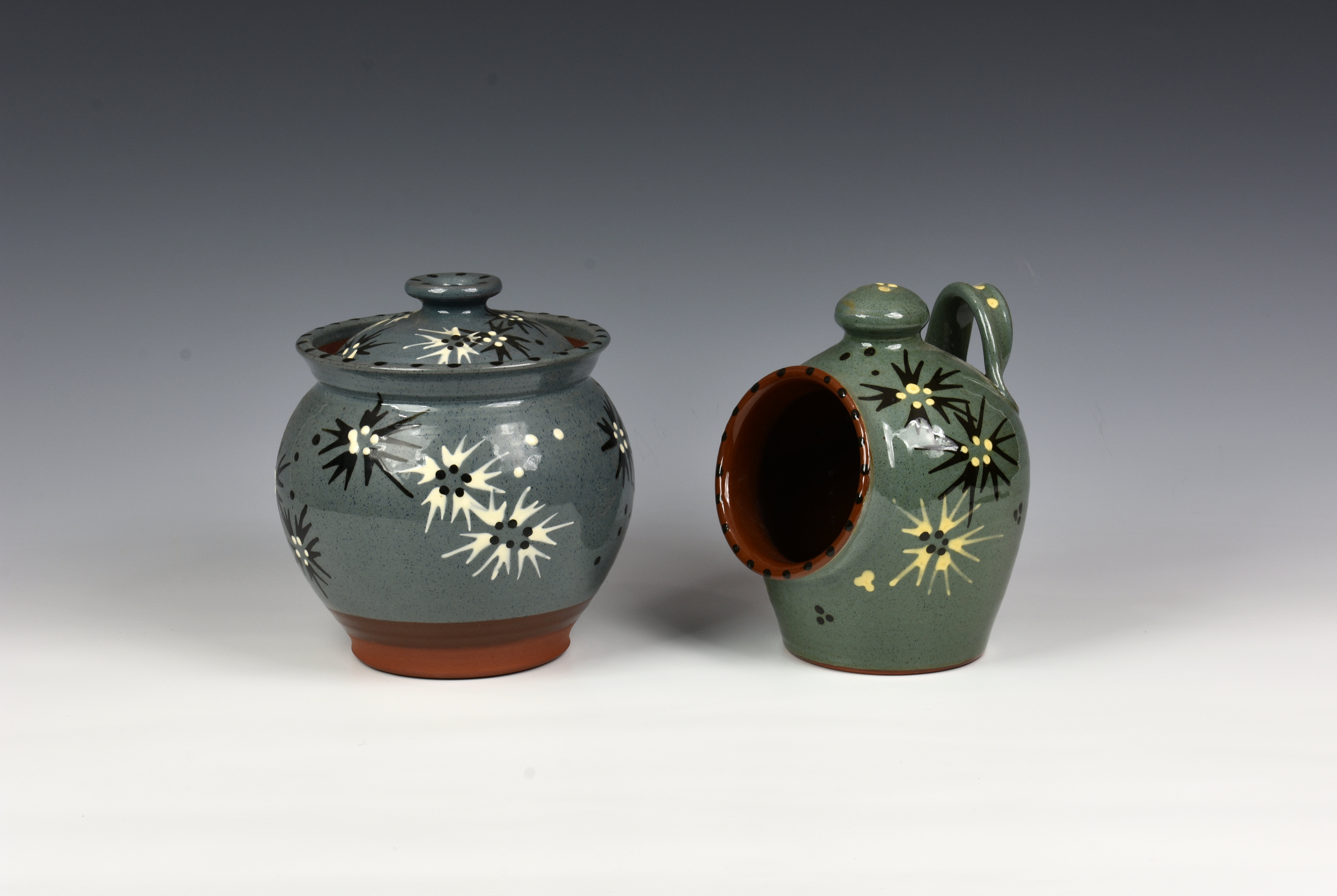 A Guernsey Pottery jar and cover, of ovoid form, raised on a unglazed circular foot, decorated