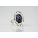 An antique diamond and sapphire plaque ring, featuring an inky blue cabochon sapphire to the centre,