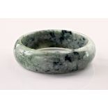 A contemporary jade bangle, of greyish green and white marbled colouring and with a diameter of