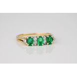 A 14ct yellow gold, emerald and diamond ring, the larger 3 oval cut emeralds set between 6 smaller