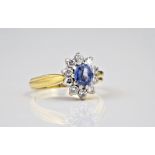 An 18ct gold, sapphire and diamond cluster ring, the cornflower blue oval cut sapphire within a