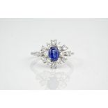 An 18ct white gold, sapphire and diamond dress ring., The oval cut sapphire weighing approximately
